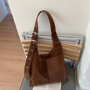Minimalist brown suede tote bag with adjustable silver buckle on a wooden chair