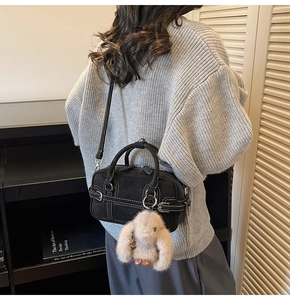 Detail view of a black vintage bowling bag with white stitching and cute rabbit charm