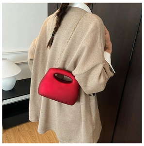 Chic red structured acrylic evening bag with gold chain strap shown on a model