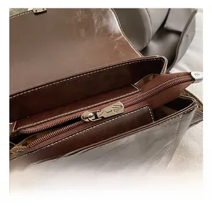 Macro view of brown leather handbag featuring silver zipper with triangle embossed logo