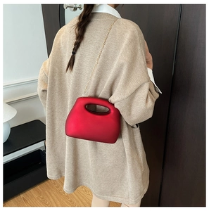 Red matte geometric acrylic box bag shown crossbody on a model in a casual setting