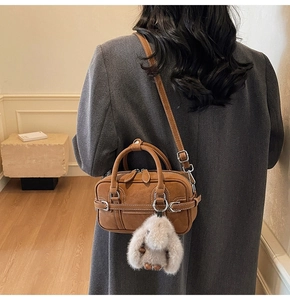 Brown suede pillow bag featuring a plush bunny pendant and adjustable shoulder strap