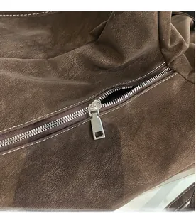 Detailed macro view of the smooth metal zipper on a premium brown suede shoulder bag