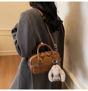 Brown faux suede underarm bag detail featuring white stitching and a cute bunny pendant