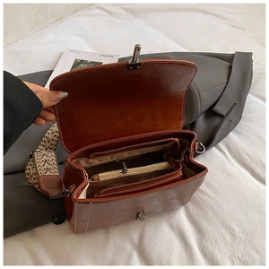 Detail of vintage brown leather crossbody bag with geometric woven wide shoulder strap