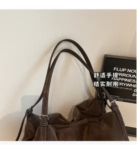 Close-up of brown suede tote bag handles with durable silver metal adjustable buckles
