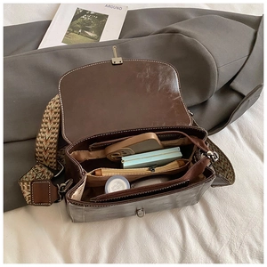 Internal compartments of a vintage dark brown leather bag with a wide woven strap
