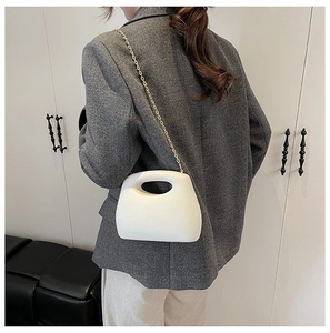 Minimalist white acrylic crossbody bag with gold chain worn by a model in a modern style