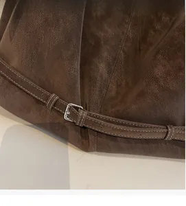 Detail of dark brown suede bag showing decorative strap with silver buckle and white stitching