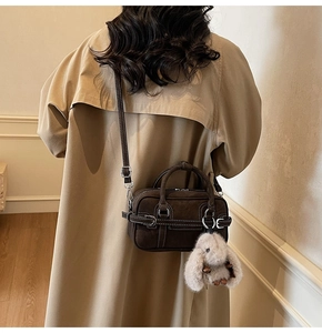 Detail of dark brown vintage pillow bag with contrast stitching and rabbit charm