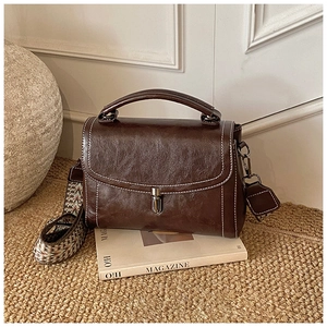 Detail of retro dark brown leather bag with contrast stitching and ethnic woven strap
