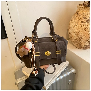 Detail of vintage messenger bag with metal clasp and horse charm on a suitcase