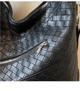 Detail of premium black woven leather tote featuring a smooth silver metal zipper closure