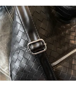 Close-up of adjustable leather shoulder strap with silver buckle on a woven tote bag