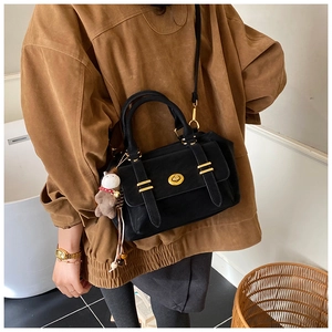 Close-up of black retro messenger bag with golden twist lock and a pony charm accessory