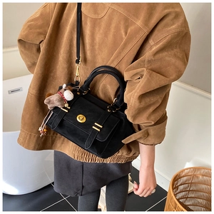 Close-up of vintage black messenger bag with gold clasp and brown horse charm detail