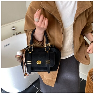 Close-up of black retro messenger bag with golden twist lock and cute bear charm