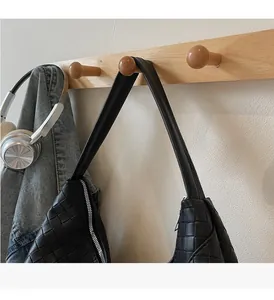 Close-up of black woven tote bag texture with silver zipper hanging on a wooden hook