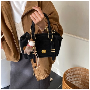 Detail of black vintage messenger bag with gold hardware and a cute brown horse charm