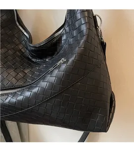 Detailed view of black woven leather texture and silver zipper on the tote bag