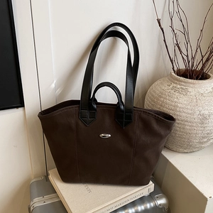 Große dunkelbraune Tote-Bag mit schwarzen Ledergriffen und Schnalle auf silbernem Koffer