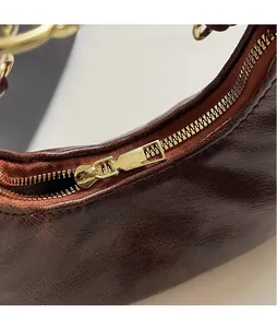 Macro shot of durable golden metal zipper and glossy puller on retro brown handbag