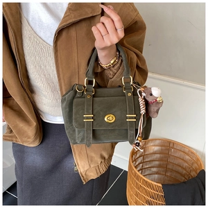 Detail of dark green suede messenger bag with gold hardware and horse charm