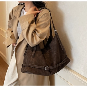 Close-up of vintage brown suede tote bag featuring adjustable straps and buckle details