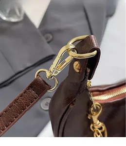Detail of high-quality gold metal hooks on dark brown lychee textured leather bag