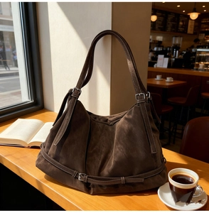 Detail of vintage brown suede hobo bag with adjustable metallic buckle and soft texture