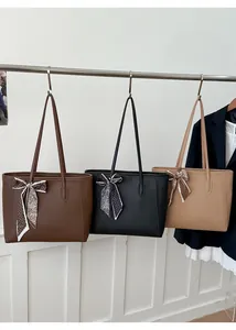 Detail of three tote bags in brown, black, and khaki with stylish ribbon bow accents