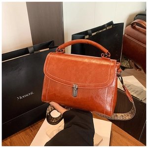 Close-up of retro orange-brown handbag featuring a metal twist lock and woven strap
