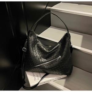 Detail of black woven leather tote bag with metal zipper and adjustable strap