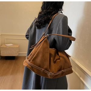 Detail of soft dark brown suede tote bag with leather strap and silver metal buckle