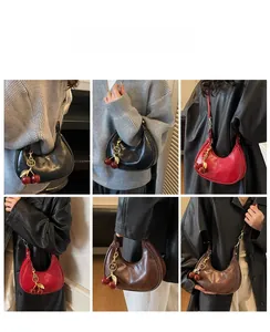 Detail showing retro crescent shoulder bag with a unique cherry charm in various colors