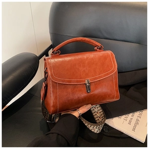 Detailed shot of retro brown handbag with woven shoulder strap and silver metal clasp