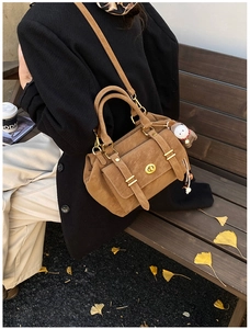 Brown vintage suede messenger bag with gold hardware on a park bench with autumn leaves