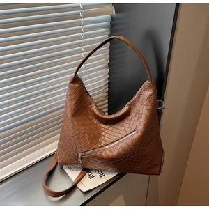 Close-up of woven leather texture on a brown shoulder bag with silver zipper detail