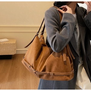Detail of soft brown suede shoulder bag with long strap and fine stitching finish