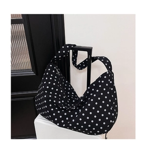 Detailed shot of large capacity black polka dot tote bag hanging on a white suitcase handle