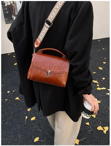 Detail of vintage brown leather bag with geometric woven strap on an autumn background