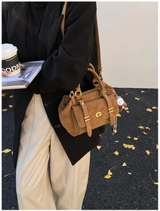 Detail showing vintage brown suede messenger bag with gold hardware and plush charm