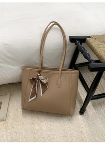 Detail of khaki tote bag featuring lychee texture and floral scarf on handle