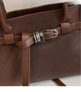 Close-up of brown textured leather with silver triple-ring metal buckle detail