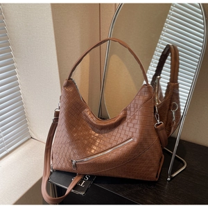 Detail showing the brown woven texture and decorative diagonal zipper on the leather hobo bag