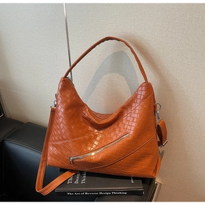 Detail of orange woven leather hobo bag showing texture and diagonal zipper pocket design