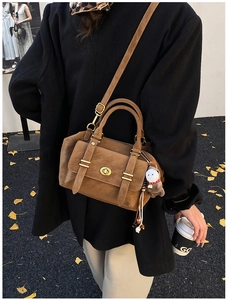 Detail of vintage brown messenger bag with gold hardware and plush horse charm