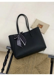 Close-up of black litchi leather tote bag with polka dot and paisley silk scarf detail