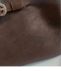 Close-up of deep brown pebbled leather texture with fine stitching and silver metal buckle