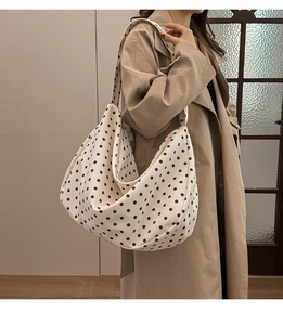 Spacious beige polka dot canvas hobo bag worn on shoulder for casual daily commute